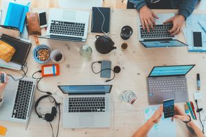 team working around a table on laptops 