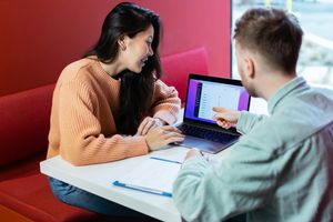 two people discussing work around a laptop 